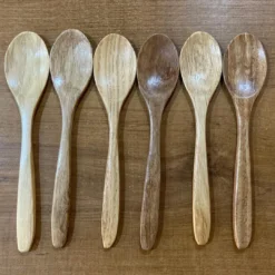 6 Wooden spoons for eating are placed together in a row on a wooden desk.