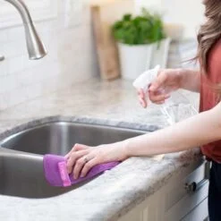 Women is wiping sink and kitchen table using kitchen cleaning towel