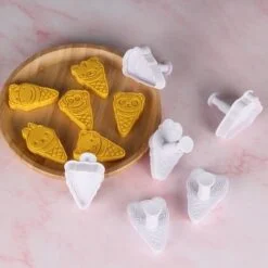 White color ice cream cookie cutter presented in different designs besides plate full of cookies