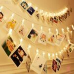 A string of warm white LED lights with 20 sturdy clips displaying photos and artwork on a wall.