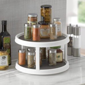 The double-layer rotating tray placed on a kitchen countertop with other kitchen items around it, demonstrating its space-saving design