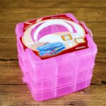 Three-layer plastic transparent jewelry storage box with 18 compartments in each layer. The box has a carrying handle and comes in a random prominent color.