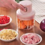 The electric garlic mincer in operation, chopping garlic cloves inside the transparent container.