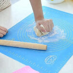 Multifunctional Versatility: Silicone Baking Sheet & Fondant Rolling Mat Set A large, rectangular silicone baking sheet displayed next to a smooth silicone fondant rolling mat with measurement markings.