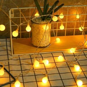 Warm Glow: 20 LED Globe String Lights for Inviting Ambiance A strand of 20 LED Globe String Lights illuminated, casting a warm white glow. The individual bulbs are spherical and spaced evenly along the black string.