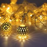 A strand of Metal Ball LED Light with 20 spherical metal bulbs, illuminated and casting a warm white glow. The string light is draped across a dark background.