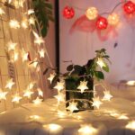 14 LED Small Star String Diwali Lights A warm white 14 LED Small Star String Light, featuring delicate star-shaped bulbs, draped across a headboard. It creates a captivating and cozy ambiance.