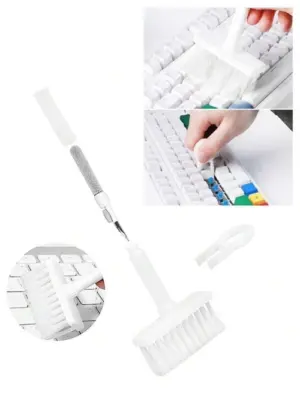 The 5-in-1 cleaning brush being used to clean a laptop keyboard, with the high-density brush removing dust and the metal pen tip reaching tight spaces around keys.