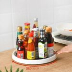 A person effortlessly spinning the rotating storage tray to access spices stored on a kitchen countertop.