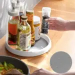 A person effortlessly spinning the rotating storage tray to access spices stored on a kitchen countertop.