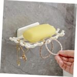 A wall-mounted soap dish holding a bar of soap and a sponge, demonstrating its versatility for various bathroom needs.