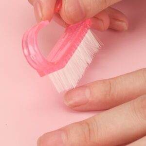 A person using a nail cleaning brush to remove dirt from under their nails, demonstrating the brush's reach and ease of use.