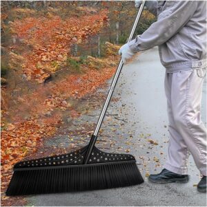 A person using the wide outdoor angle broom to sweep leaves or debris on an outdoor surface.