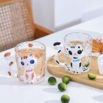 This image showcases a charming glass coffee & tea cup featuring a cute animal design. The design adds a touch of whimsy to your morning routine or tea time. The cup is suitable for enjoying hot or cold beverages.