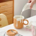 The biscuit pattern ceramic coffee mug in use, filled with a hot beverage (coffee, tea) and possibly placed on a saucer.